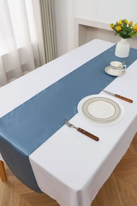 Detail shot of smooth blue satin table runner texture on white tablecloth for wedding decor