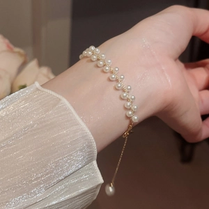 Détail du bracelet élégant en perles double rang avec chaîne dorée et fermoir ajustable