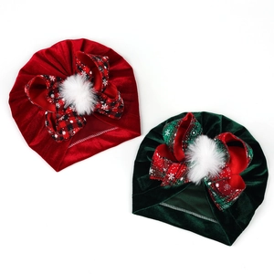 Detail of red and green velvet baby turbans with plaid bows and white faux fur pom-poms