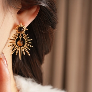 Close-up of bohemian gold sunburst earrings with round tiger eye stones on a model