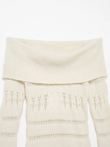 Detail of hollow-out knit pattern on creamy white off-shoulder sweater texture