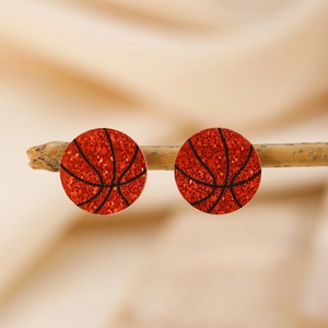 Détail macro de boucles d'oreilles basketball orange pailleté sur bois naturel