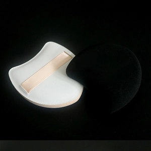 Detail of white leather-textured puff and black flocked makeup sponge on black background