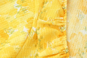 Detail of yellow floral seersucker fabric with ruffled texture and delicate floral print