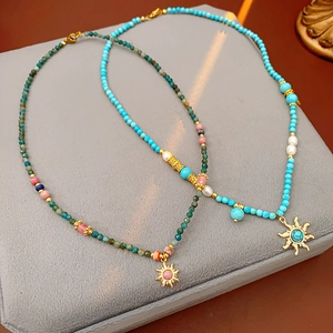 Détail de colliers pendentif soleil avec perles turquoise et perles d'eau douce