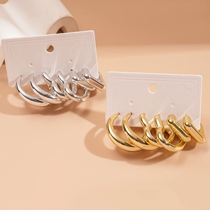 Set of 6 pairs of gold and silver geometric hoop earrings in various sizes on display