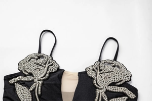 Detail of elegant black swimsuit featuring crystal rose embellishments and mesh insert