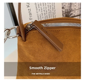 Detail of smooth silver metal zipper on vintage brown suede tote bag with leather puller