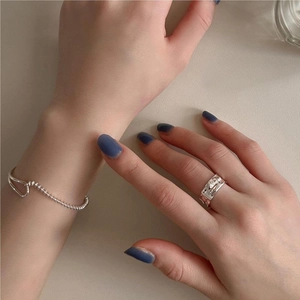 Detailed view of minimalist S925 sterling silver beaded bracelet and textured ring on model