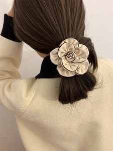 Detailed view of camellia hair tie with black edge on low ponytail accessory