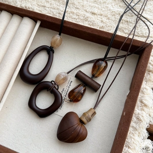 Close-up of wood and resin pendants with heart-shaped carving and geometric beads