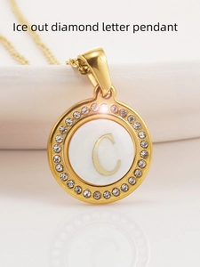 Vue macro d'un collier en acier titane 18K avec pendentif lettre C en nacre glacée