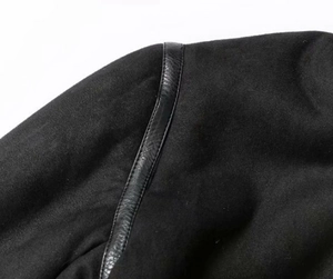 Détail des coutures en daim et cuir sur le blouson aviateur noir en peau lainée