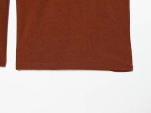 Detailed view of brown fabric texture and precise stitching on the hem of wide-leg pants