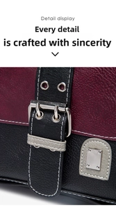 Macro shot of two-tone burgundy and black leather saddle bag with silver buckle and white stitching