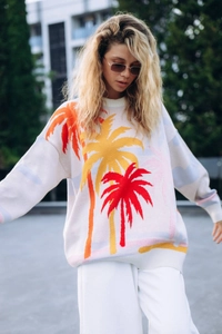 Detail of cream knit sweater showing vibrant jacquard coconut tree patterns and texture