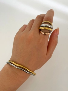 Detail of stacked multi-layered gold and silver rings and wave bangles on hands
