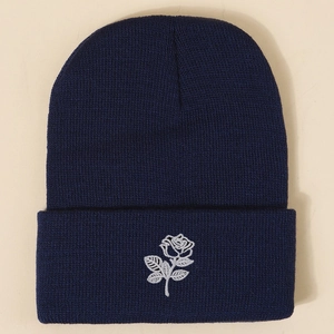 Navy blue knitted beanie with white rose embroidery featuring a classic cuffed design