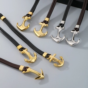 Close-up of anchor pendants in gold and silver finish with braided leather cords