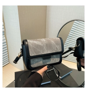Detail of black and grey contrast crossbody bag with gold hardware and denim texture