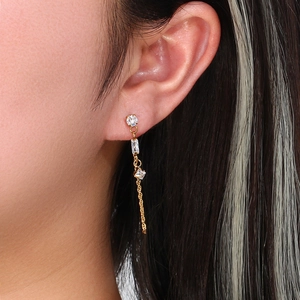 Macro shot of long gold chain earrings with sparkling round and geometric cubic zirconia