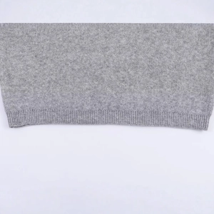 Light gray knit sweater detail with textured wool fabric and ribbed hem finish