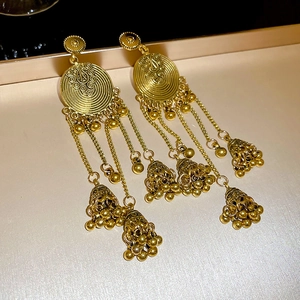 Detail of vintage gold flower earrings with ethnic tassels and jhumka bell pendants