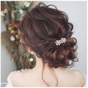 Détail d'épingles à cheveux fleurs en perles et strass sur une coiffure de mariée