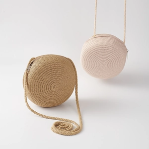 Detail of round straw woven bags in khaki and cream with zipper and long shoulder straps