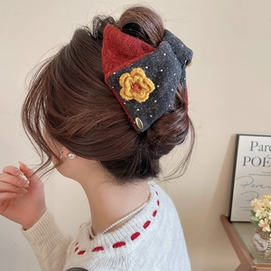 Detail view of red and grey wool hair claw with crochet flower in a soft updo hairstyle