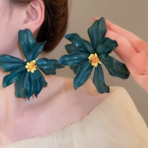Detail of oversized dark green acrylic flower earrings with vibrant yellow center pistil