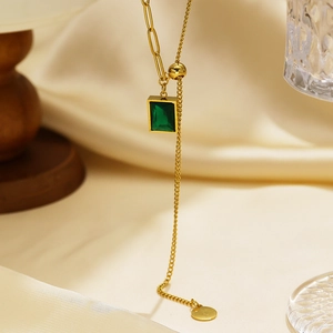 Elegant gold necklace with rectangular emerald green zircon pendant on silk background