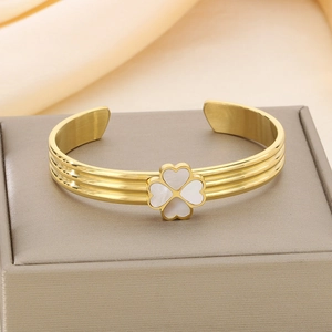 Détail d'un bracelet trèfle en acier doré avec incrustation de nacre et anneau nervuré
