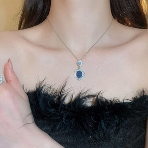 Close-up of a silver necklace with sparkling blue oval gemstones on a model's neck