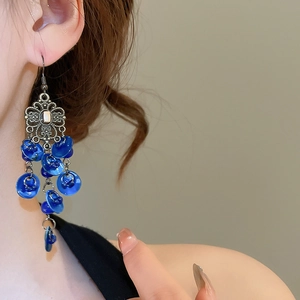 Close-up of bohemian earrings with blue discs and vintage silver floral tassels