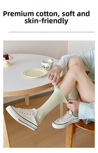 Detailed view of light green thin cotton socks with white canvas shoes on a wooden chair
