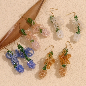 Detailed view of colorful beaded flower earrings with gold hooks on a leaf