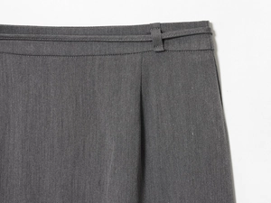 Dettaglio gonna in twill grigio scuro con trama del tessuto, passanti e pieghe in vita