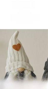 Detail of knitted Christmas gnome with heart patch, braided beard and wooden nose