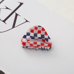 Detail shot of a small checkered hair claw clip with red white and blue pattern