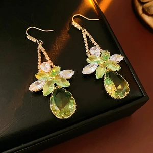 Detail of green zircon flower teardrop earrings on black leather jewelry box display