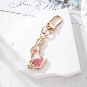 Detail of pink dried flowers inside a gold rabbit-shaped keychain with a metal clasp
