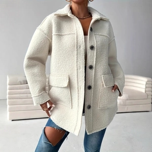 Detail of ivory sherpa jacket texture with large flap pockets and marbled buttons