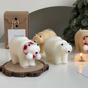 Polar bear candles with red scarves on wooden base with festive Christmas background