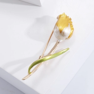 Elegant gold tulip brooch with white enamel flower and green leaf detail on white backdrop