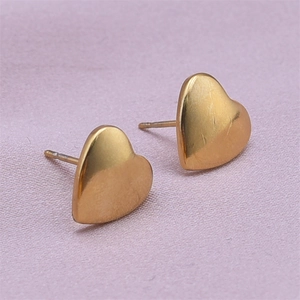 Macro shot of minimalist gold heart stud earrings in 304 stainless steel on pink fabric