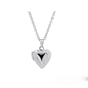 Detail view of a vintage silver heart-shaped photo locket necklace with intricate engraving