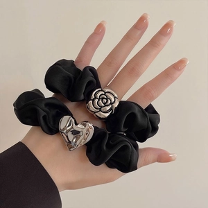 Set of two black fabric scrunchies featuring silver metal camellia flower and heart charms