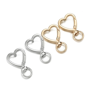Macro detail of heart-shaped aluminum lobster clasps with rotating rings in gold and silver