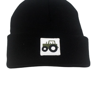 Close-up of black knitted winter hat featuring a green tractor patch for children